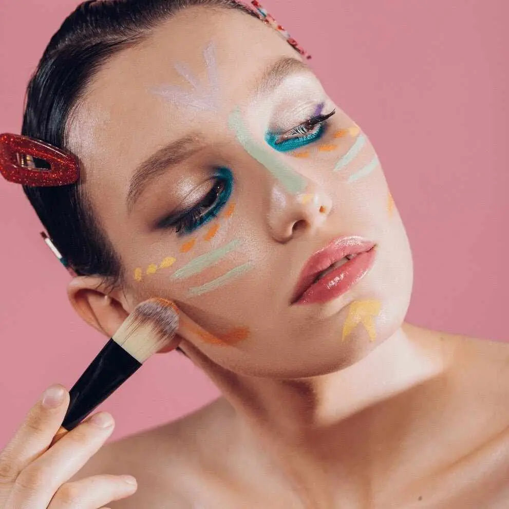 Viso donna con trucco colorato artistico applicato con pennello per correzione incarnato perfetto