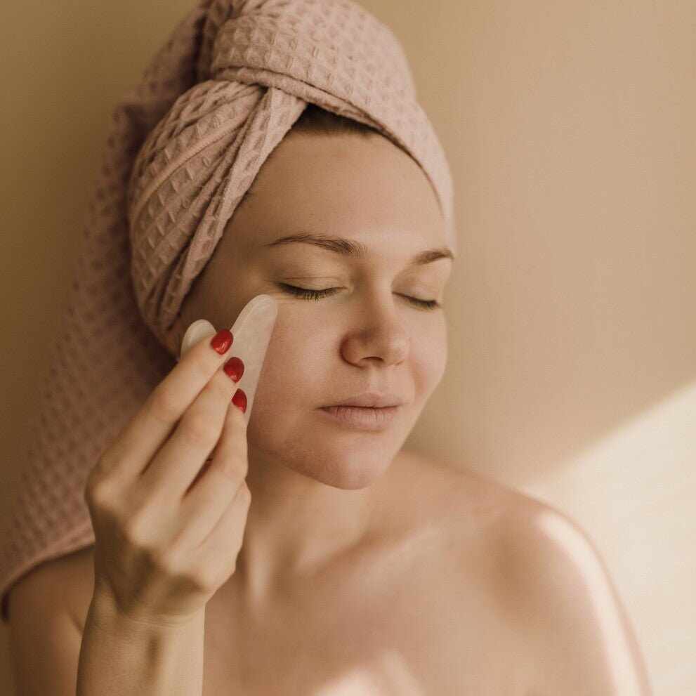 Donna usa gua sha per automassaggio drenante viso sgonfiante