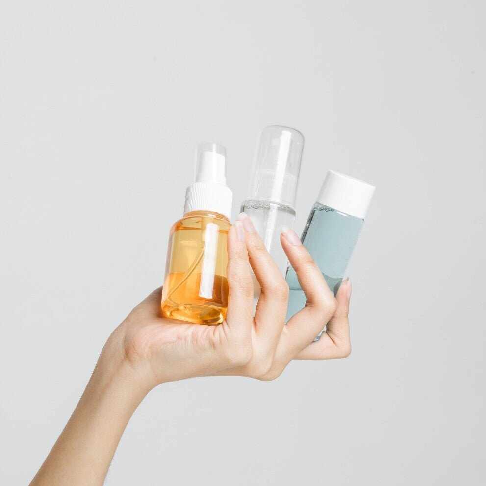 Mano che tiene tre flaconi cosmetici di varie dimensioni per campioncini senza sprechi