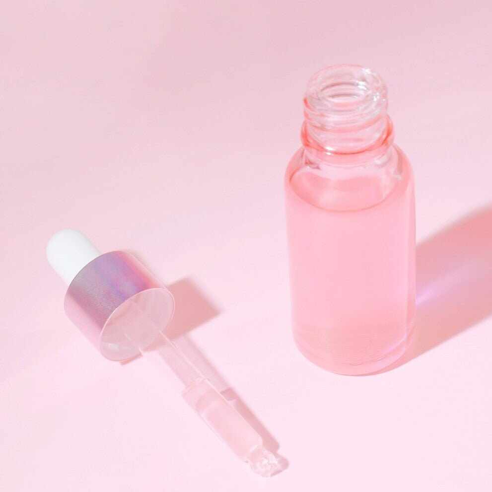 Bottiglia di vetro aperta con liquido rosa e contagocce staccato per ceramidi skincare