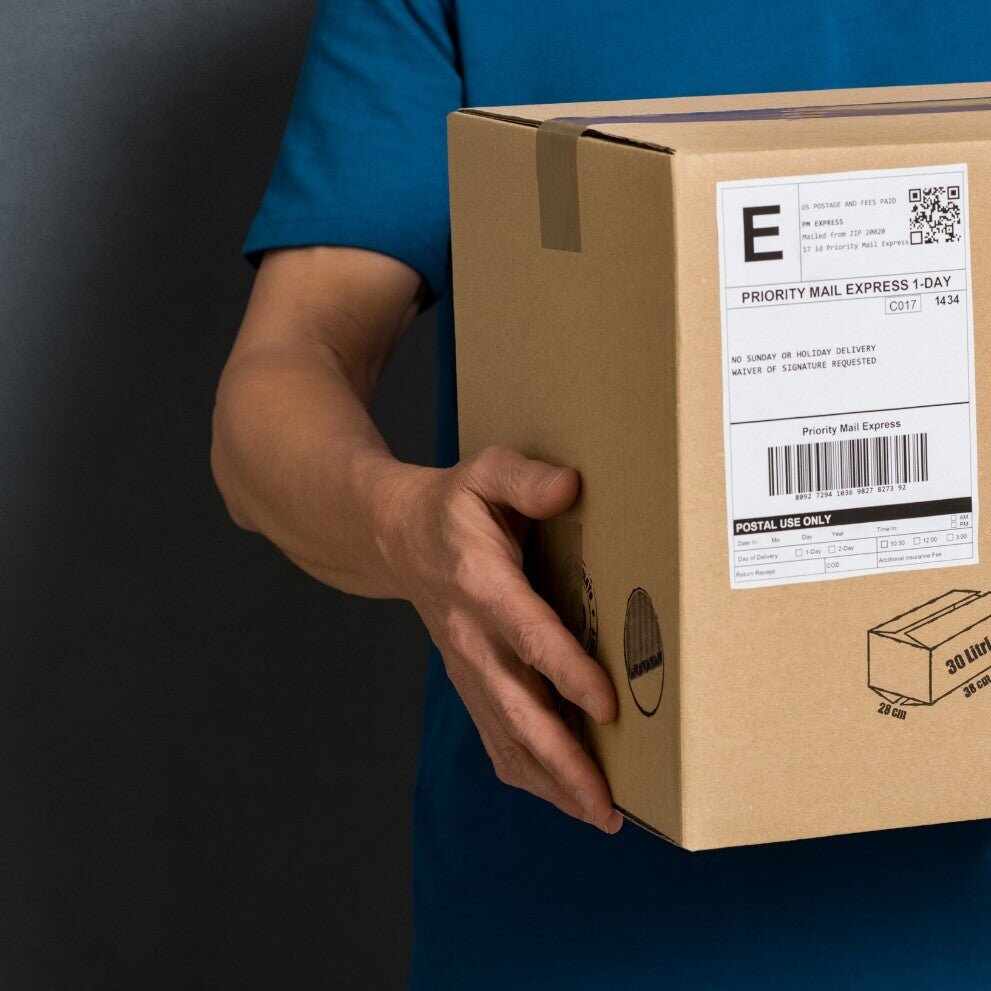 Persona che tiene scatola cartone marrone con etichetta bianca per spedizione Yumibio