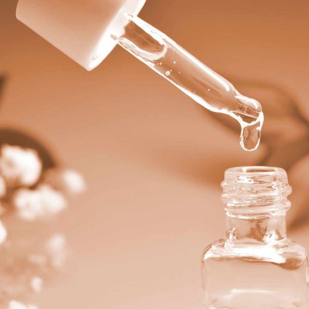 Liquido chiaro che gocciola da un contagocce in una boccetta per cosmetici al pullulano