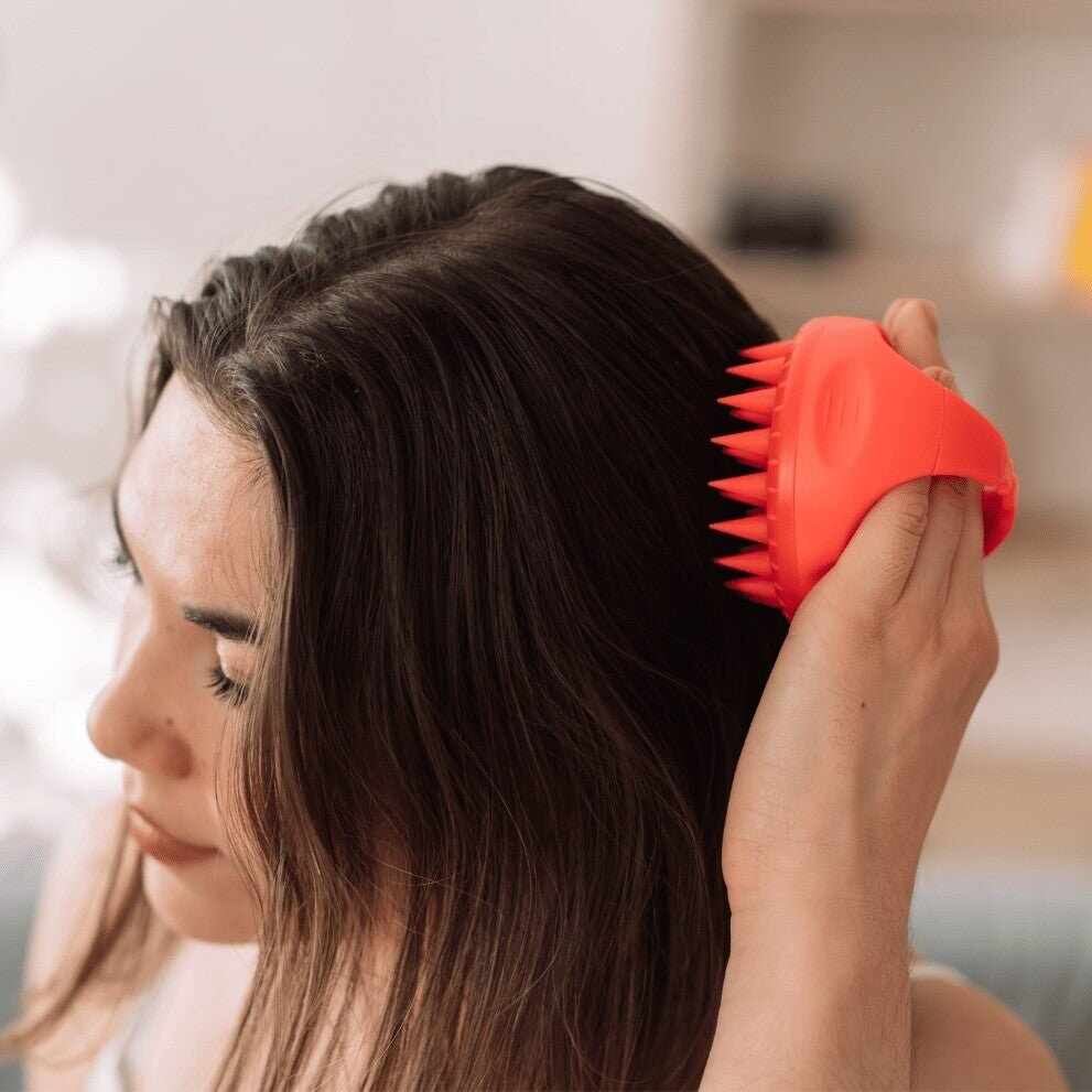 Donna usa massaggiatore silicone rosso per cuoio capelluto su capelli scuri