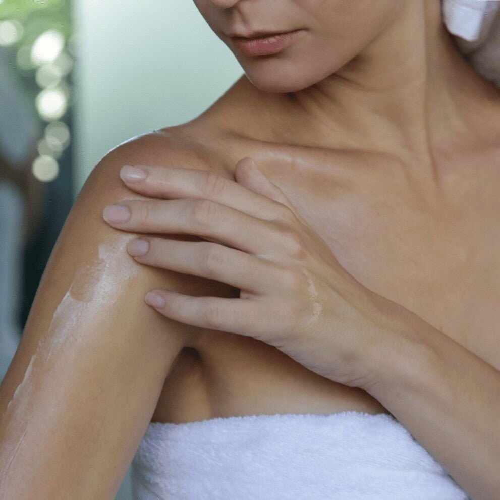 Donna applica crema idratante su braccio e spalla per dermatite atopica