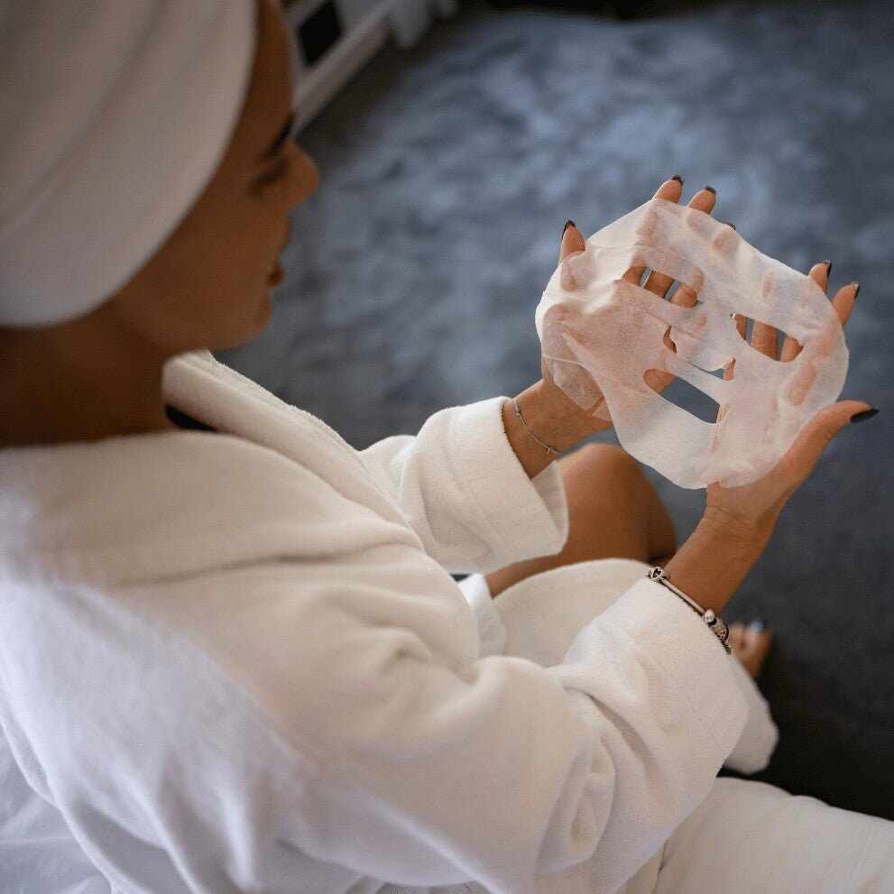 Donna in accappatoio bianco con maschera viso in tessuto