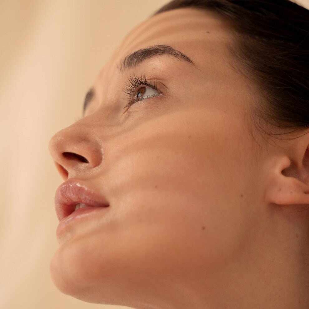 Viso donna con trucco naturale delicato e streak di luce, per prevenire macchie cutanee