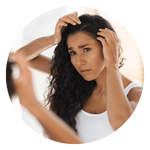 Donna con capelli lunghi scuri ricci controlla preoccupata il cuoio capelluto allo specchio