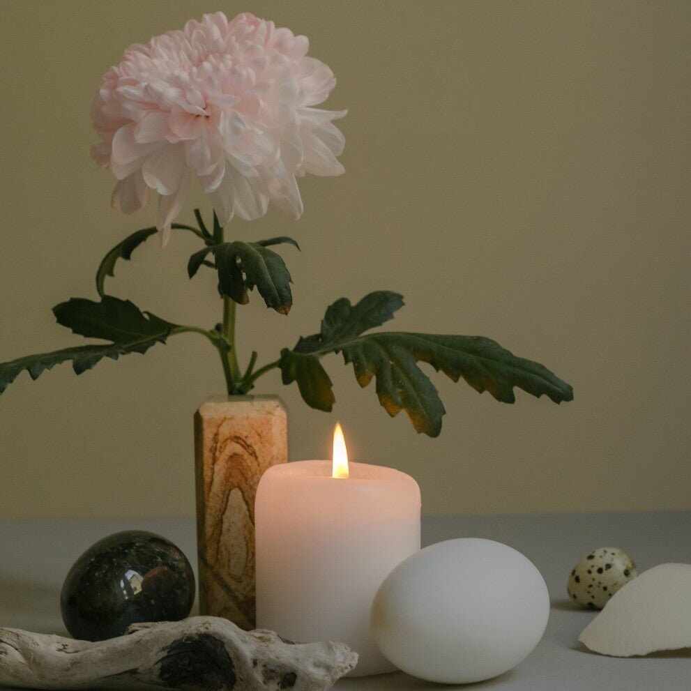 Crisantemo rosa delicato in vaso decorato, candela accesa per rituale mindfulness skincare