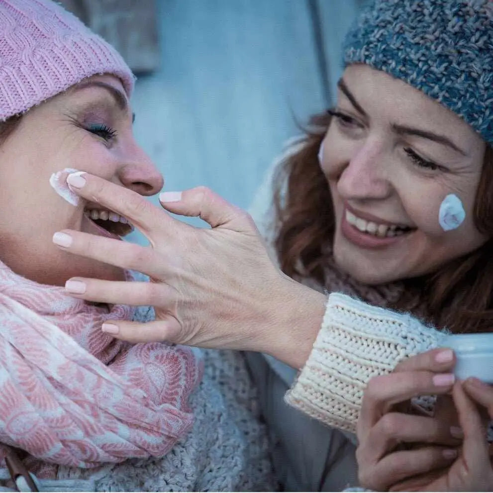 Due donne applicano crema viso nella routine skincare invernale