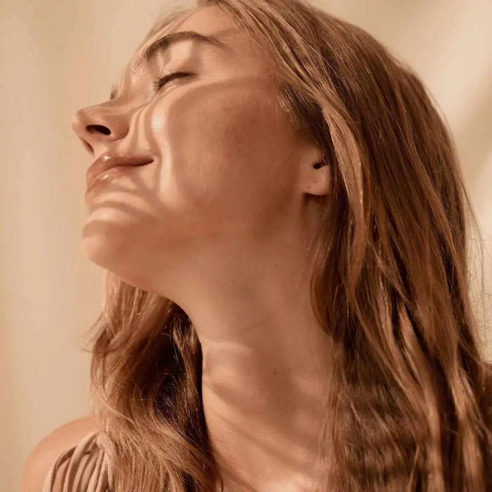 Donna con capelli castano chiaro e zigomi prominenti, illuminata da luce solare patternata, routine skincare per pelle mista