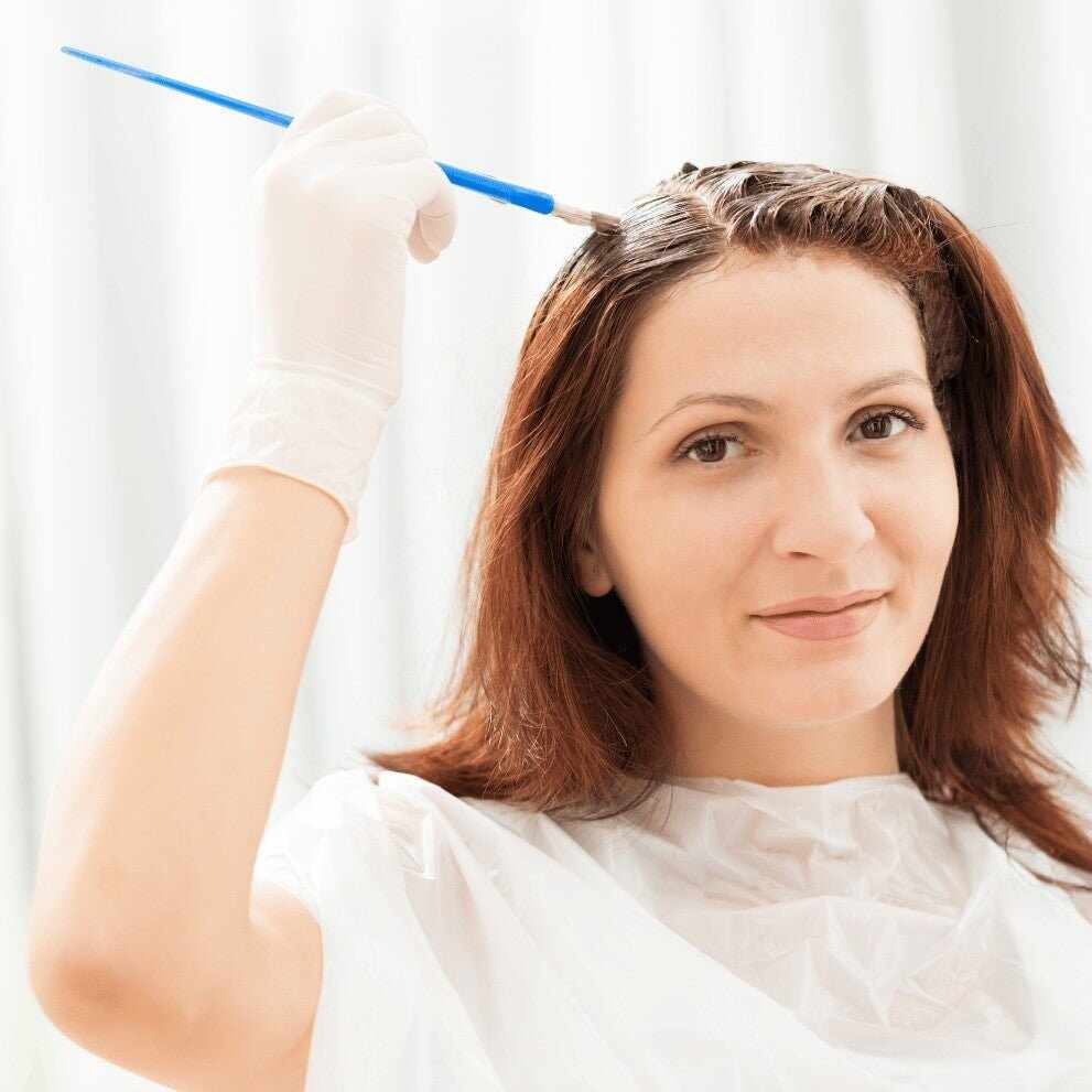 Donna che applica tinta per capelli fatta in casa con pennello