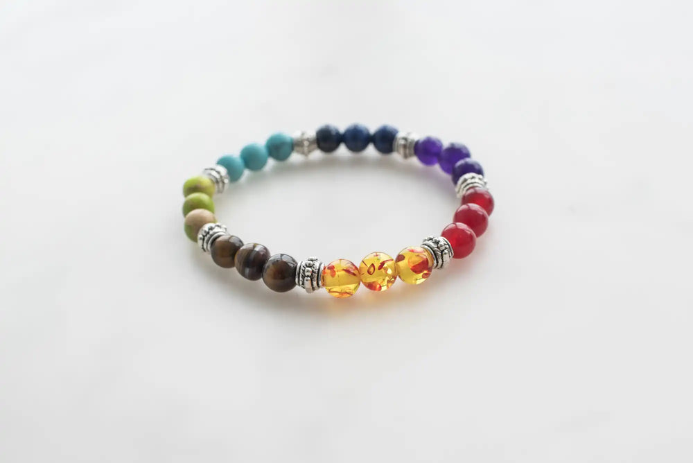 Un braccialetto colorato di chakra con perline con raccordi argentati.