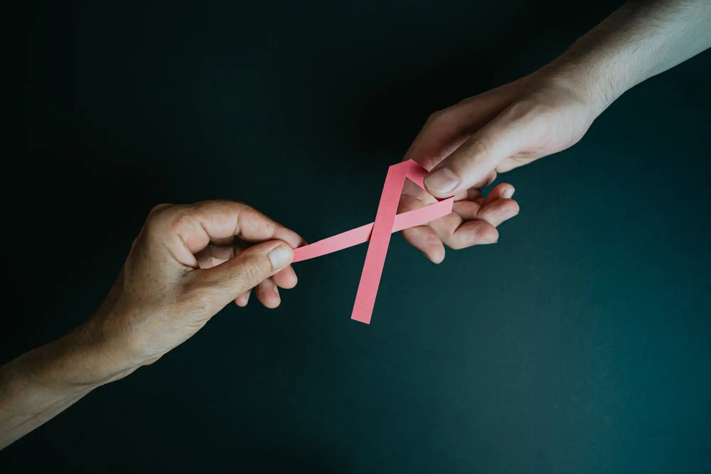 Due mani che tengono un nastro rosa di sensibilizzazione.