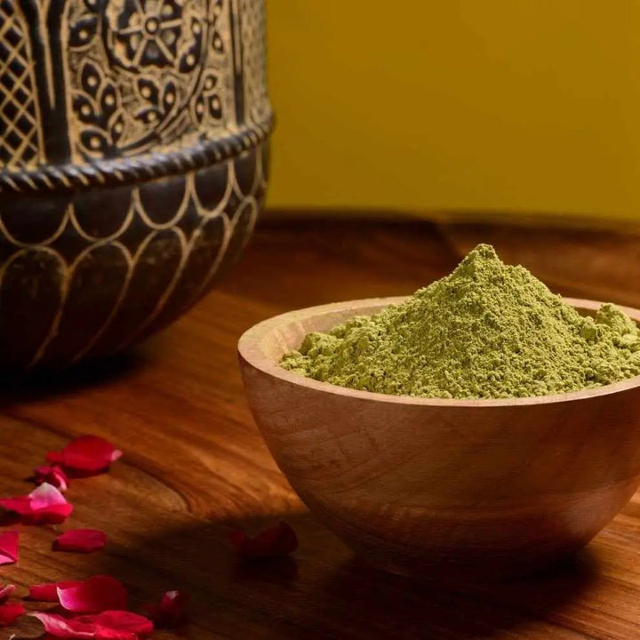 Ciotola di legno traboccante di polvere verde vibrante per henné