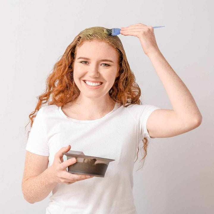 Giovane donna dai capelli rossi applica henné con pennello