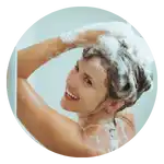 Una donna sorridente che si lava i capelli con lo shampoo.