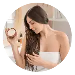 Una donna che tiene un piccolo barattolo di balsamo per capelli, applicandolo ai suoi lunghi capelli scuri e bagnati.