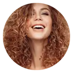 Donna sorridente con capelli ricci e voluminosi di color castano ramato.