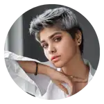 Una giovane donna straordinaria con capelli corti con riflessi argentati e trucco audace, indossa una camicia bianca con colletto.