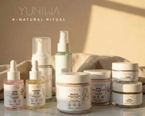Set per la cura della pelle Yunija k-natural ritual con bottiglie e vasetti in vetro e tappi bianchi, etichette trasparenti ornate da illustrazioni botaniche.